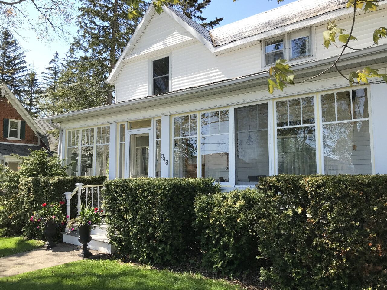 A two-story house with a covered porch, large windows, and a well-maintained garden.