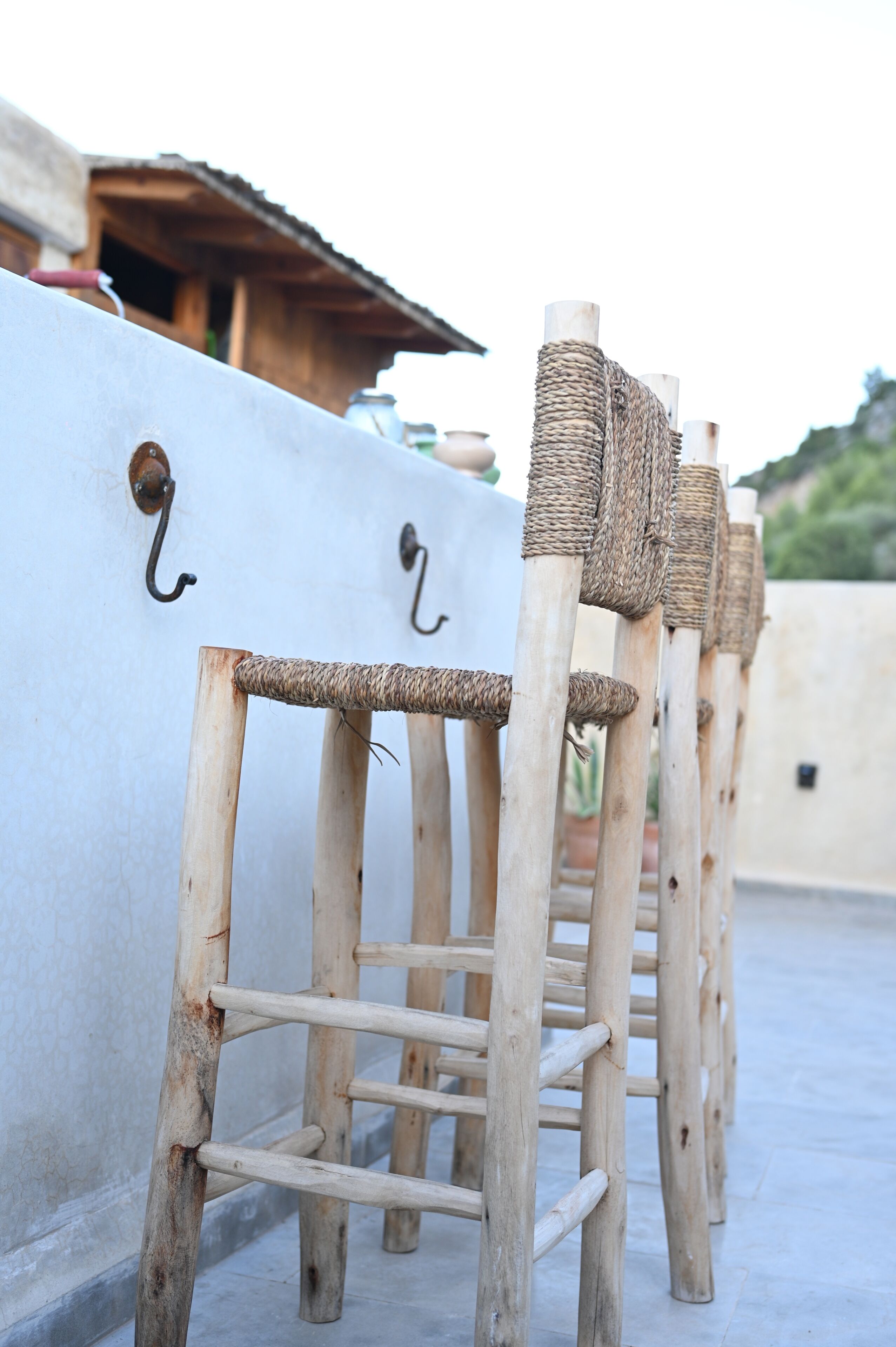 Varias estructuras de madera para gatos con cubiertas trenzadas y ganchos metálicos, sujetas a una pared blanca.