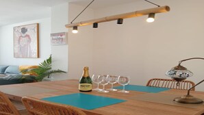 A dining area with a wooden table, four chairs, a bottle of champagne, and four wine glasses.