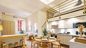 A modern kitchen with white cabinets, a wooden staircase, and a dining area with a round table and chairs. - Elegant flat with AC, heart of Nice (Nice)