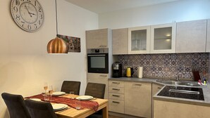 Une cuisine moderne avec un coin repas, comprenant une horloge, une machine à café et un évier.