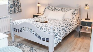 A neatly arranged bedroom with a floral-patterned bed, bedside lamps, a small bedside table, and a radiator. - NEWTOWN LODGE, pet friendly in Duncannon, County Wexford (Duncannon)