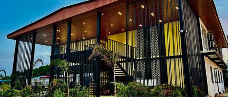 A modern building with a wooden facade, large windows, and a staircase leading to an upper level.