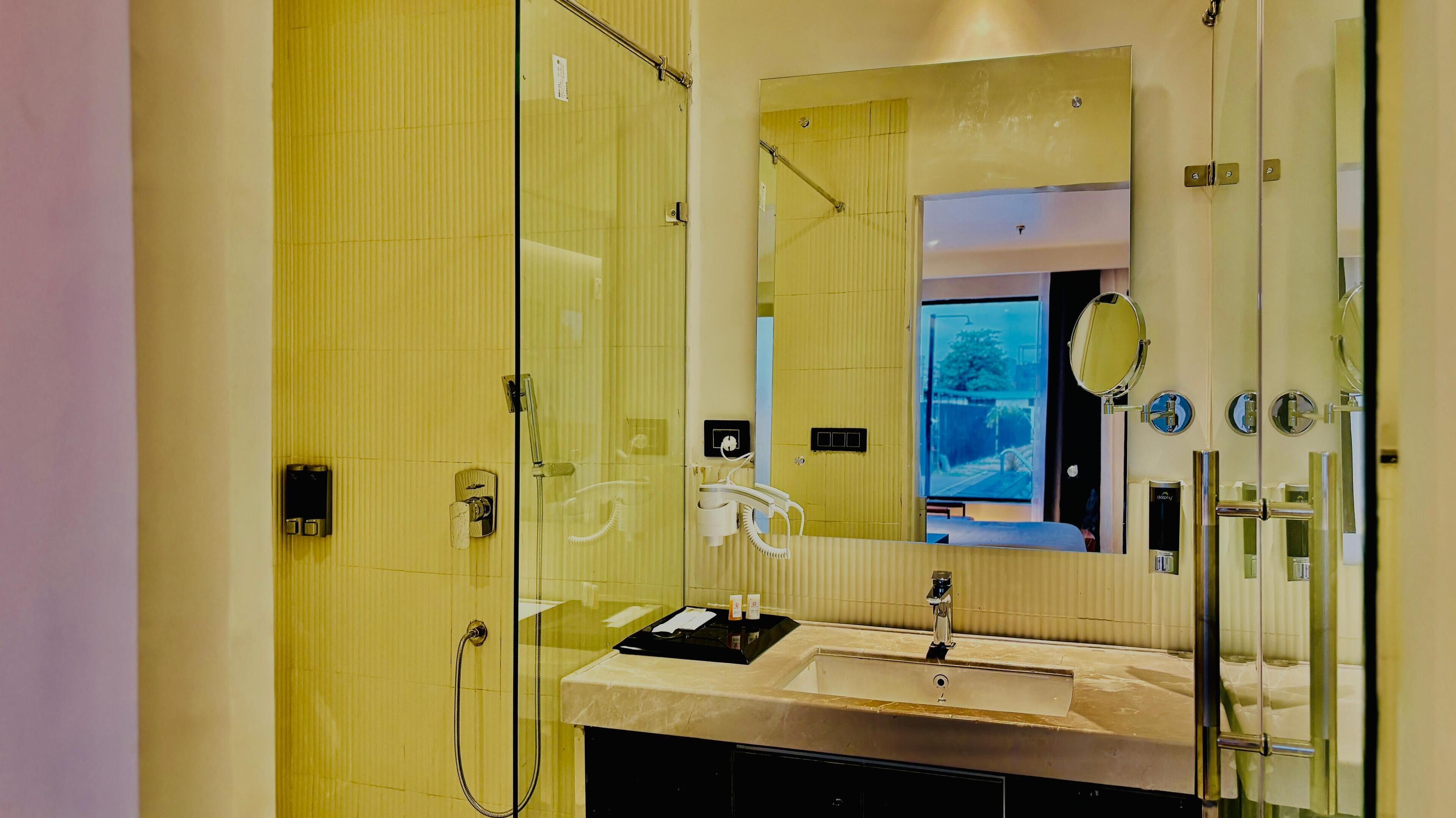 A modern bathroom with a glass shower enclosure, a sink with a vanity, and a large mirror.