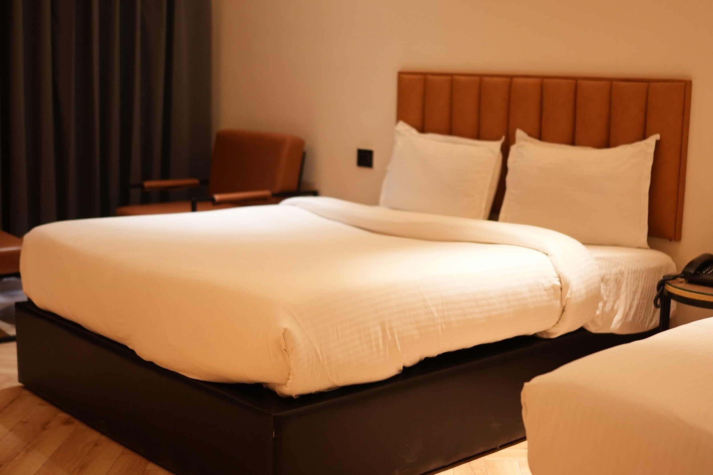 A hotel room with a large bed, a wooden headboard, and a chair.