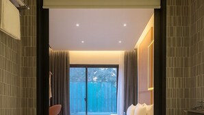 Un baño moderno con una bañera independiente, un ventanal y vistas a una cerca azul en el exterior.
