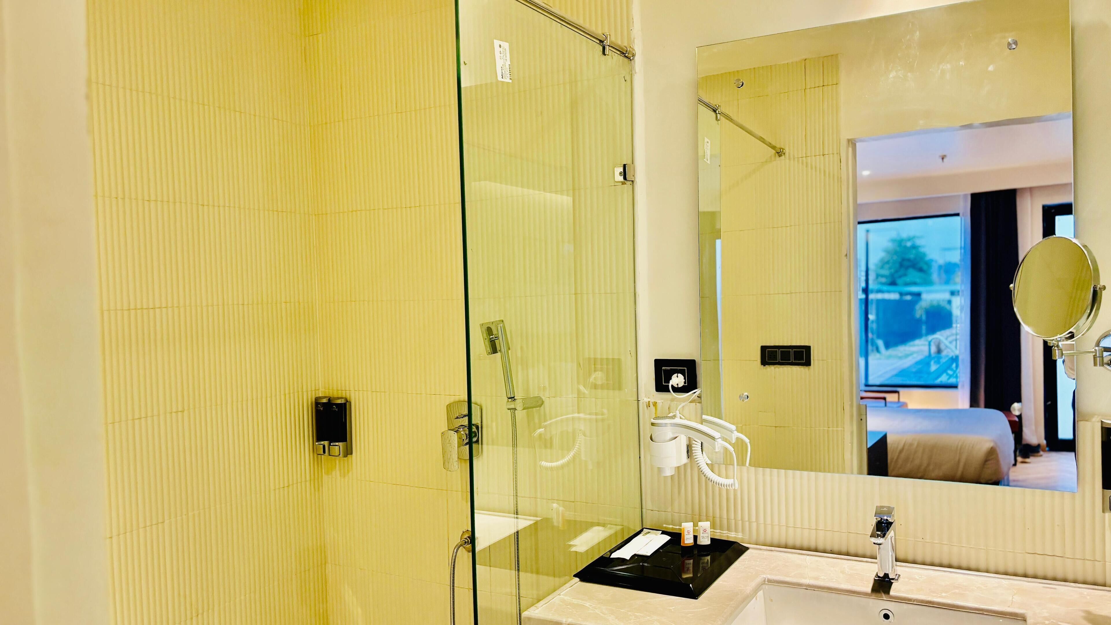 A modern bathroom with a glass shower enclosure, a vanity with a black countertop, and a large mirror.