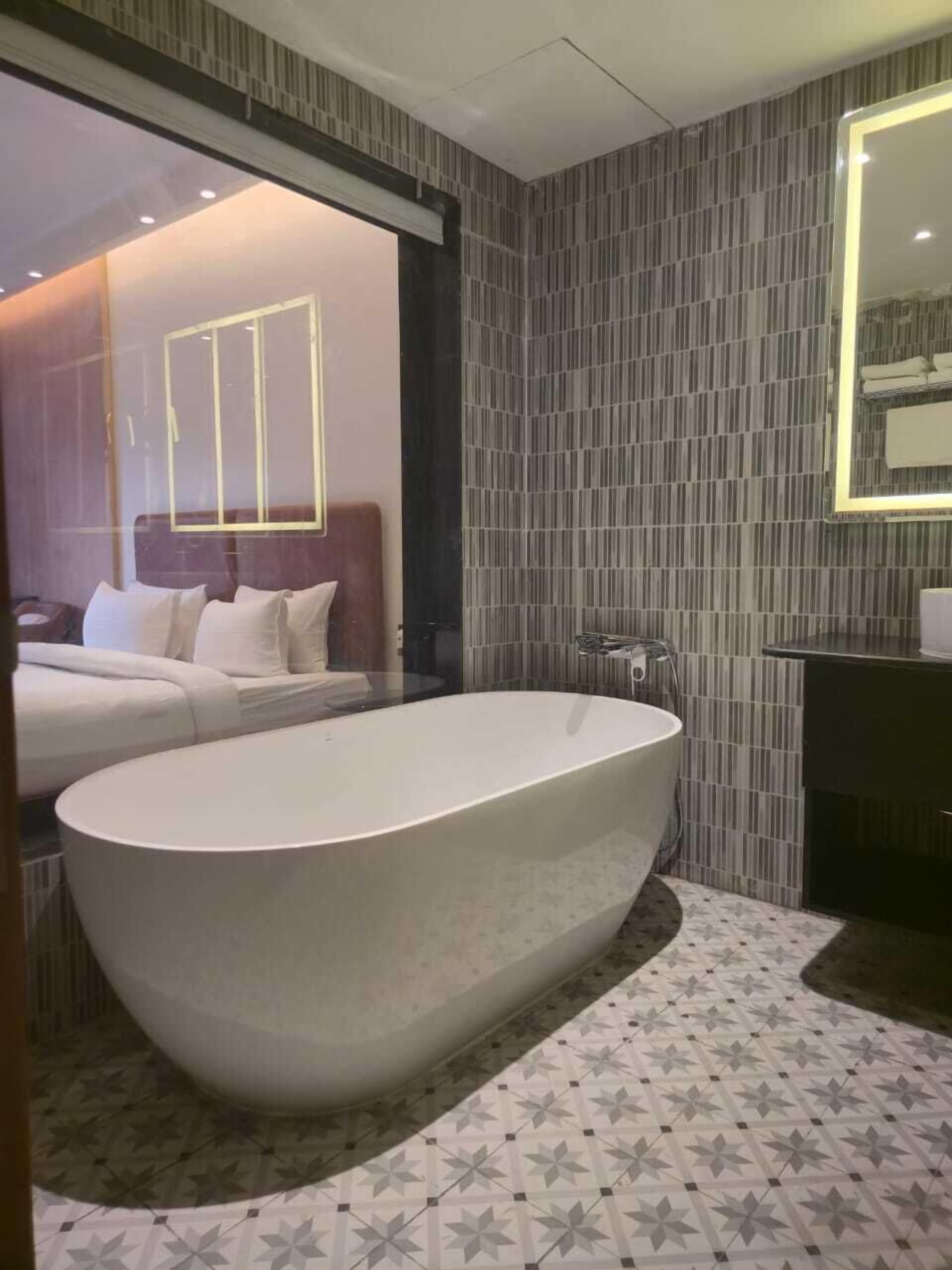 Un bagno moderno con una vasca freestanding, uno specchio grande e piastrelle decorative a pavimento.