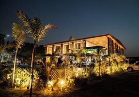 A modern hotel with a spacious outdoor pool area, surrounded by lush tropical plants and palm trees.