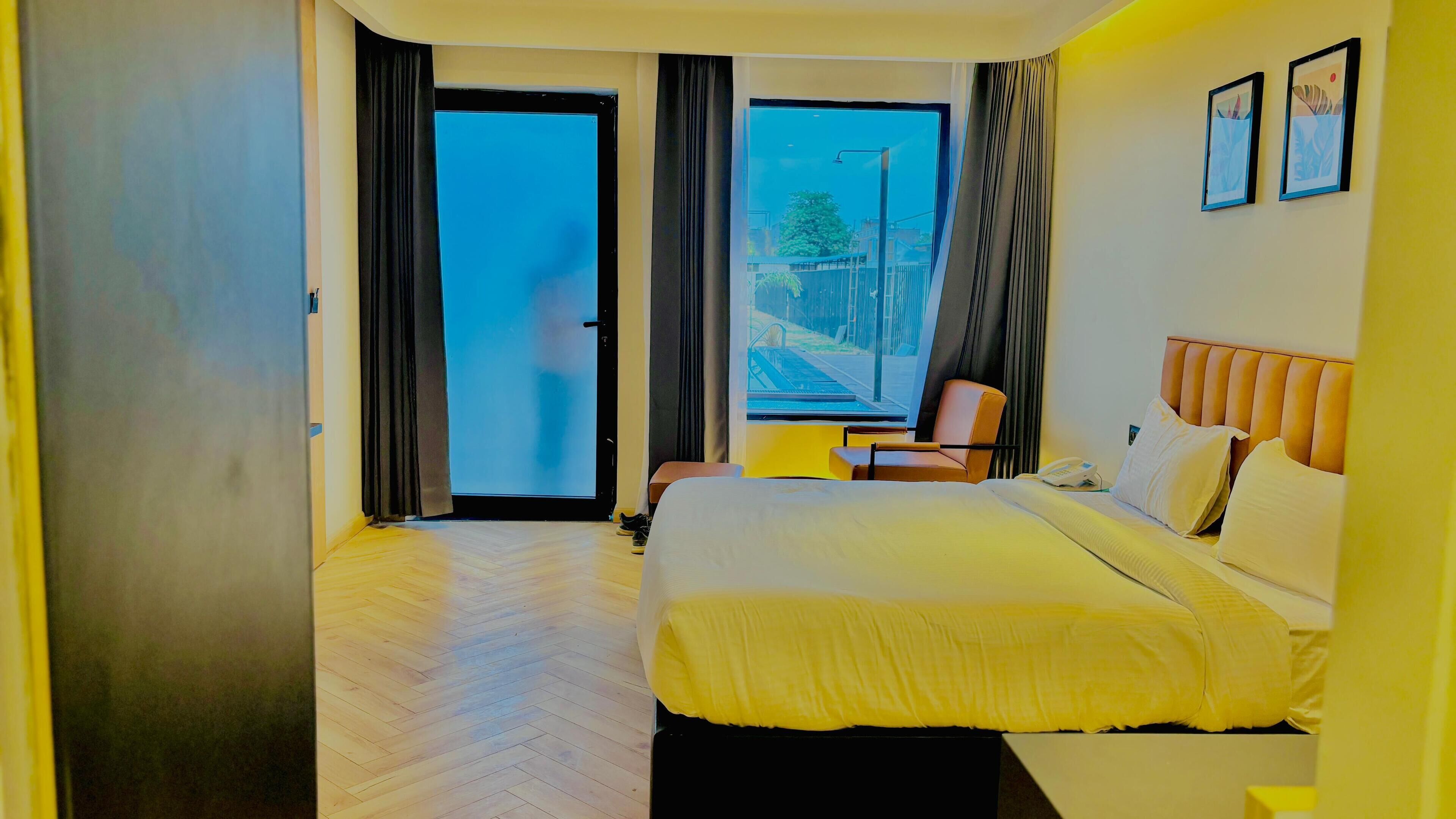 Habitación de hotel con cama, una silla, escritorio y vistas al exterior.