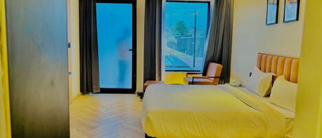 Habitación de hotel con cama, una silla, escritorio y vistas al exterior.