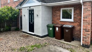 A residential property with a small garage, a black door, and two waste bins labeled for recycling and general waste. - Impeccable 3-bed House in Nottingham Free Parking (Nottingham)