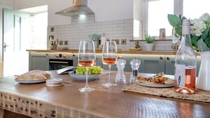 A kitchen with a wooden countertop, two wine glasses with rose wine, a bowl of green grapes, a plate of flatbread, and a bottle of rose wine. - Converted Barn with amazing views - sleeps 4 (Paignton)