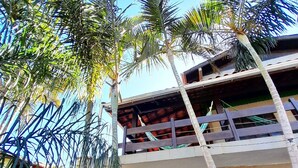 Un’area esterna su più livelli con palme, una zona relax coperta e vista sugli edifici circostanti.