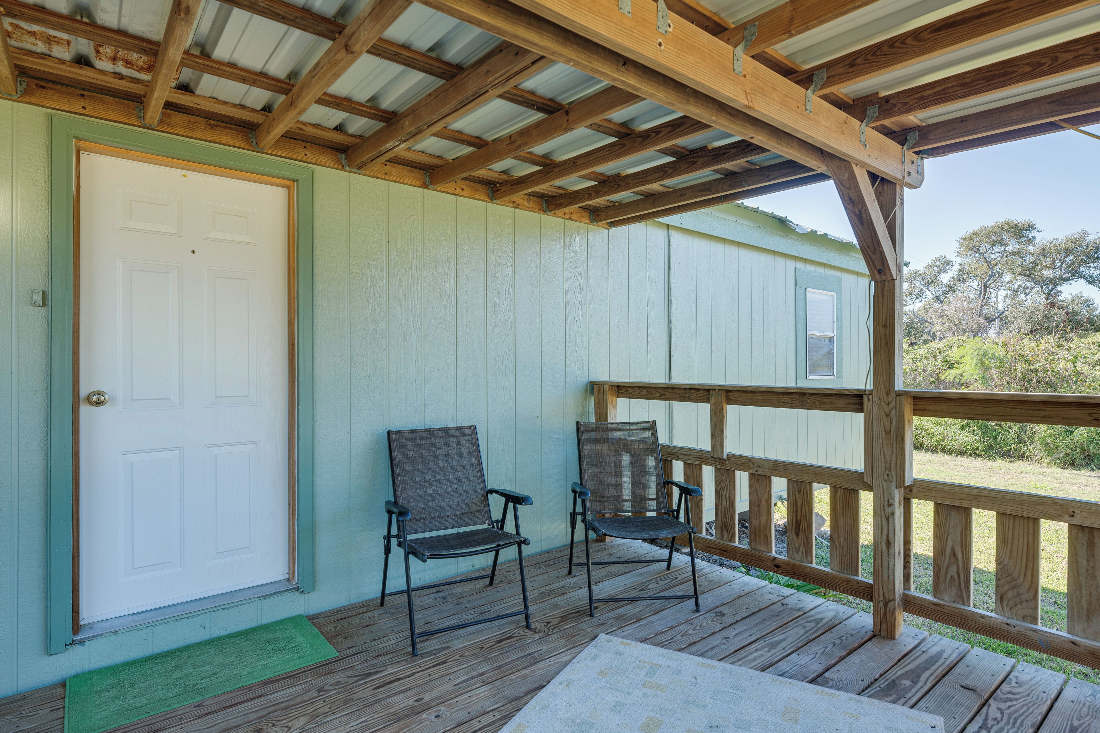 A wooden deck with two chairs and a door.