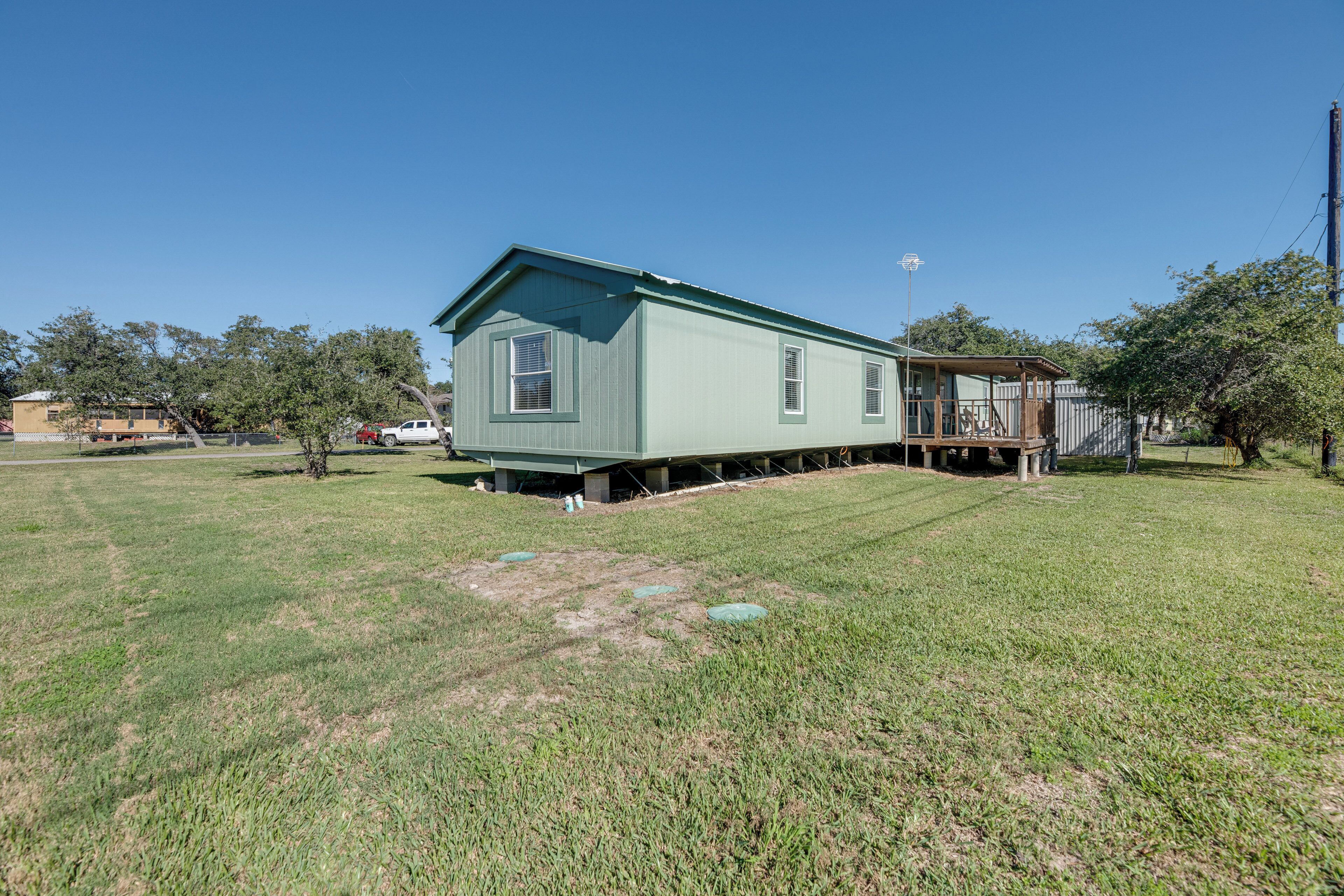 A single-story house with a green exterior, a front porch, and a small deck.
