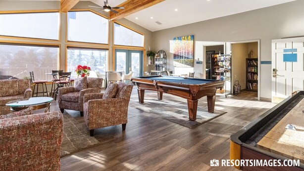 A spacious living area with a pool table, comfortable seating, and a view of the outdoors.