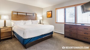 A bedroom with a bed, nightstands, a dresser, a window with blinds, and a painting on the wall.