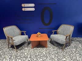 Una habitación con dos sillones, una mesita con un florero y una pared con el número '0' grande y texto en francés.