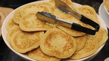 Un plato de tortitas con unas pinzas encima.