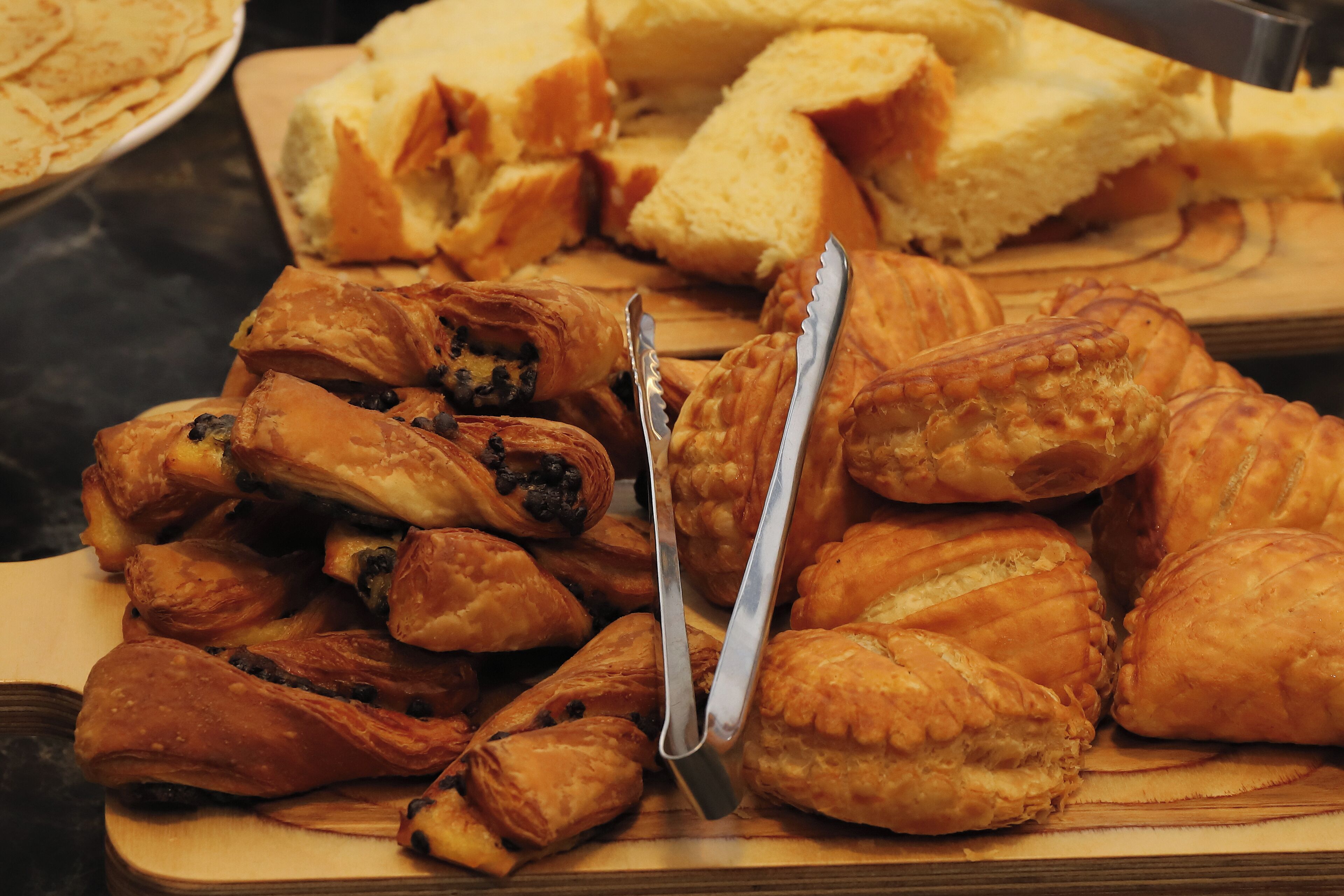 A variety of pastries on a wooden board, including croissants and other baked goods.