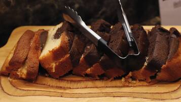 A loaf of bread with a knife and fork on a wooden cutting board.