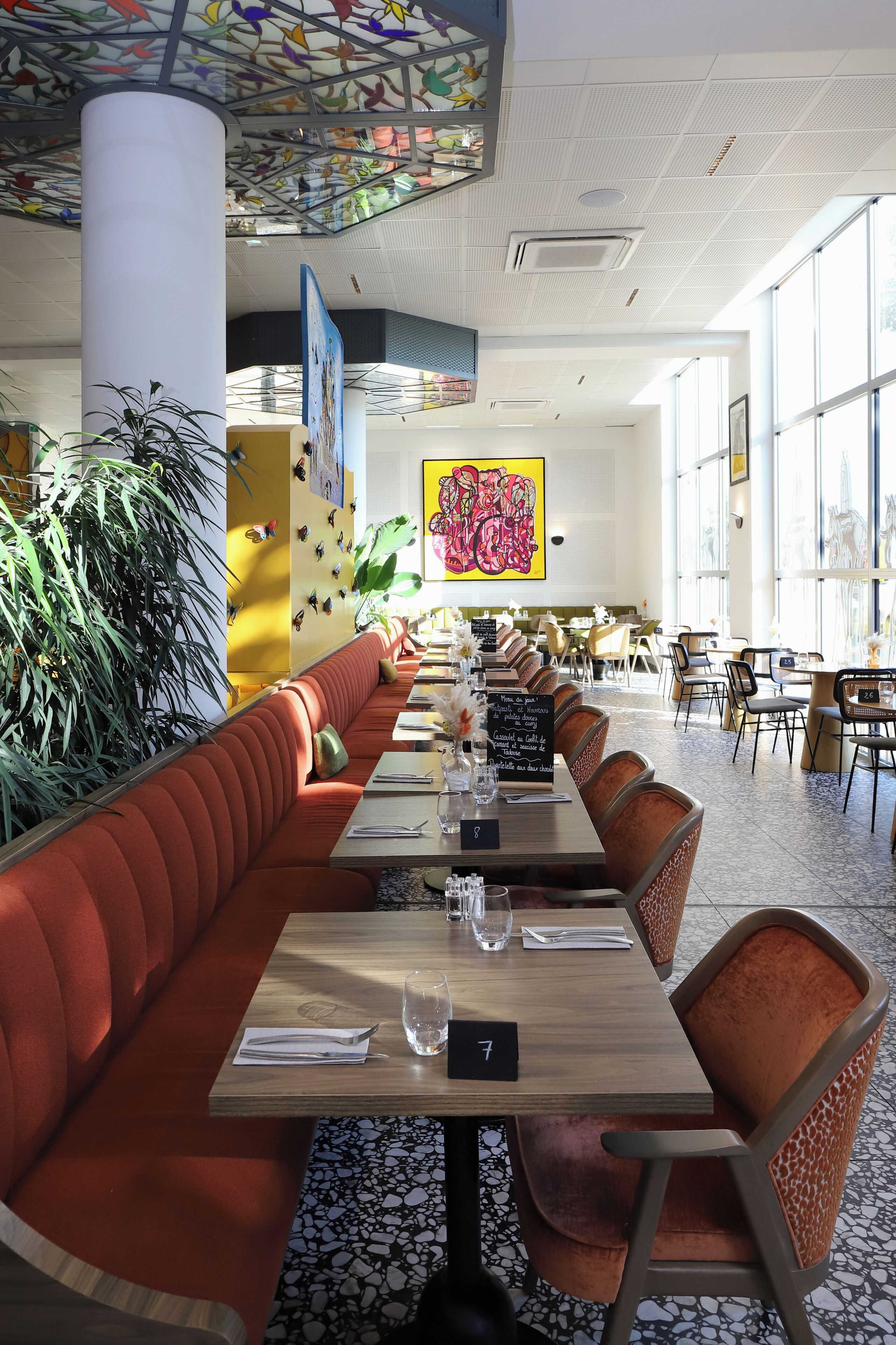 Un interior de restaurante con cabinas, mesas y un techo alto con detalles decorativos.