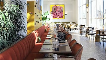 Interior de restaurante com cabines, mesas e um teto alto com detalhes decorativos.