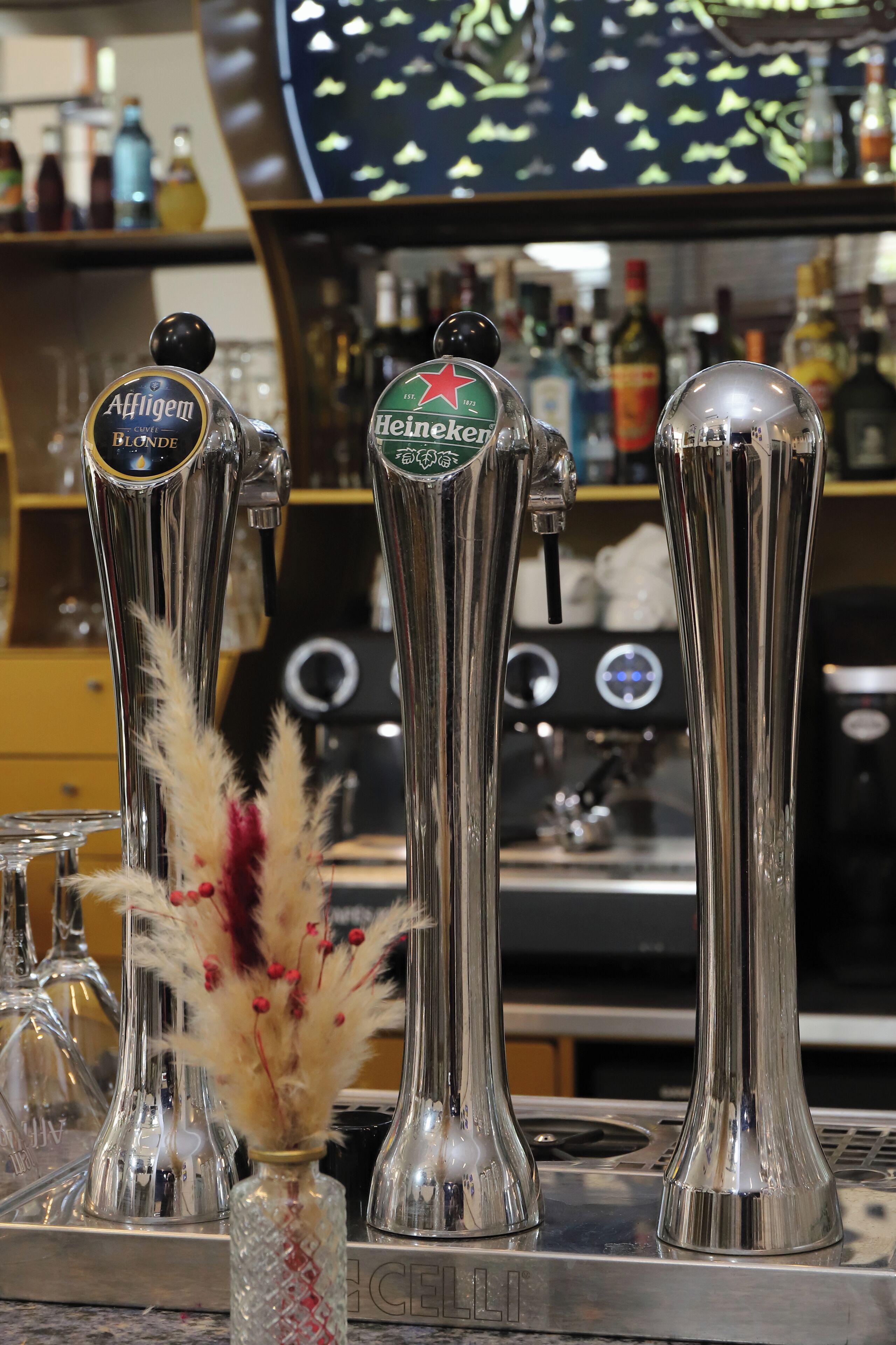Una barra con tres grifos, uno etiquetado como 'Affligem Blonde' y otro 'Heineken'.