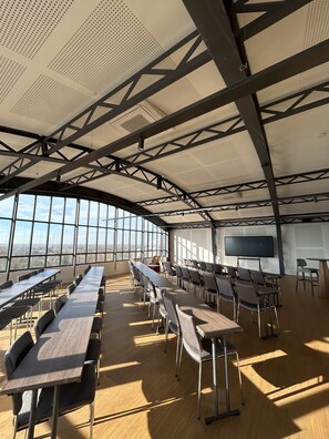 A conference room with long tables and chairs, large windows, and a high ceiling with metal beams. - Dali Hôtel Montauban (Montauban)