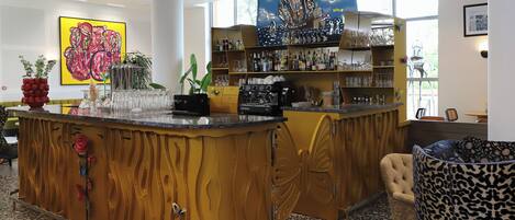 A bar area with a counter, shelves with bottles and glasses, and a large window.