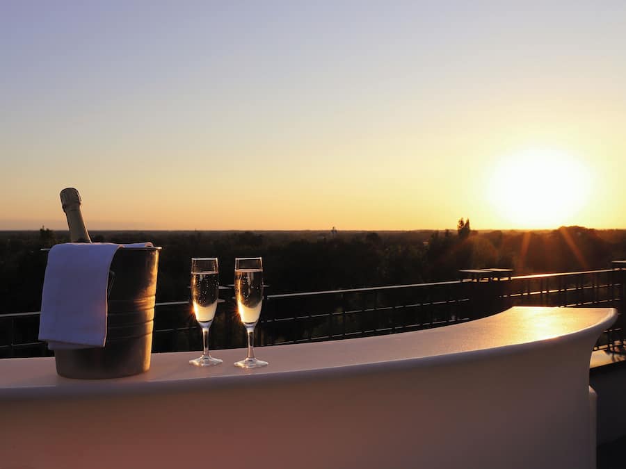 Vista al atardecer desde un balcón, con una botella y dos copas de champán.