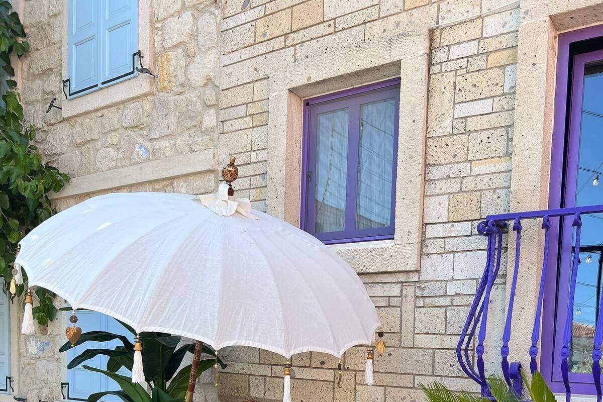 A stone building with a wooden bench and a white umbrella.