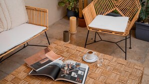 Una mesa de mimbre con revistas, una taza de café y una vela.