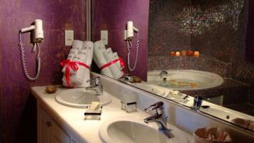 Un baño con dos lavabos, un espejo grande y una bañera. Hay toallas y artículos de aseo en la encimera.