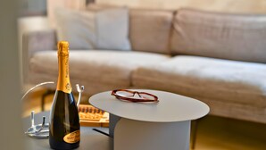 A bottle of champagne on a table with glasses and a remote control.