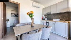 A modern kitchen with grey cabinets, a wooden countertop, and a vase with yellow flowers on the dining table.