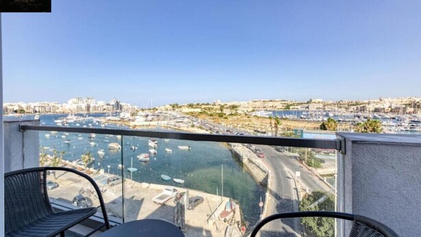A balcony with a view of a marina and cityscape.