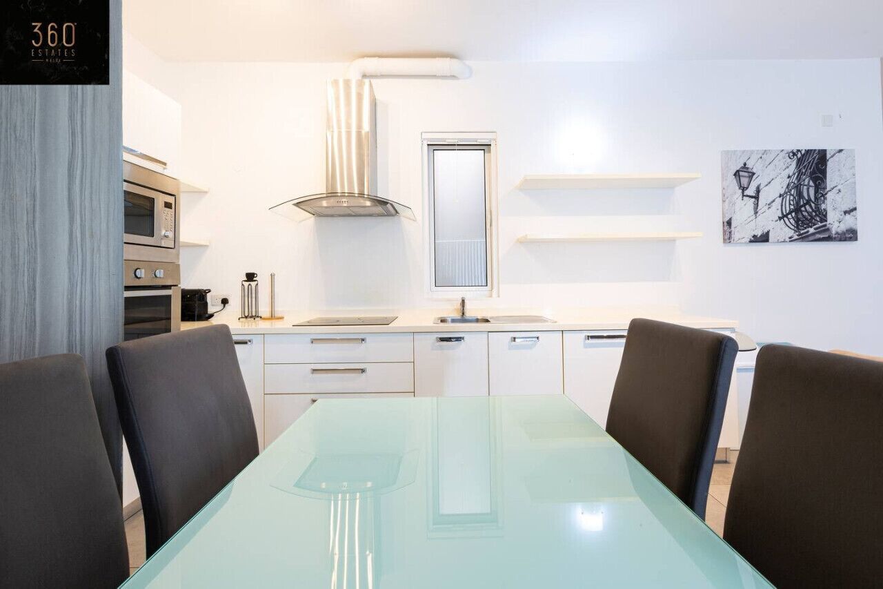 A modern kitchen with white cabinets, a stainless steel oven, a built-in microwave, and a window above the sink.