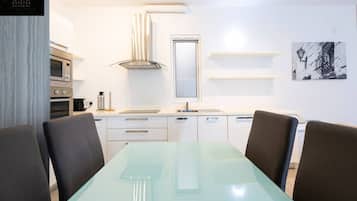 A modern kitchen with white cabinets, a stainless steel oven, a built-in microwave, and a window above the sink.