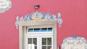 Una entrada de edificio con una puerta blanca, un letrero sobre la puerta que dice 'Snack Bar Vasso', y un letrero decorativo a la izquierda.