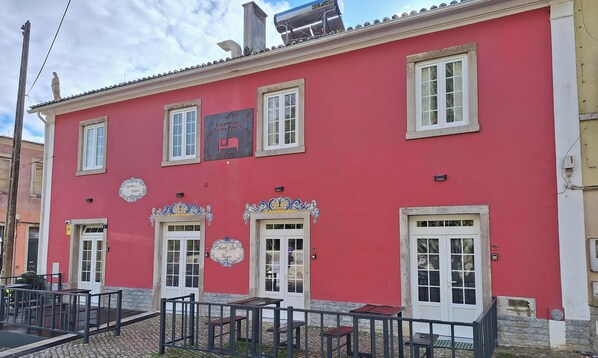 A red building with multiple windows, a balcony with tables and chairs, and a sign indicating a restaurant. -  AL Penaferrim Sintra Rooms (Sintra)