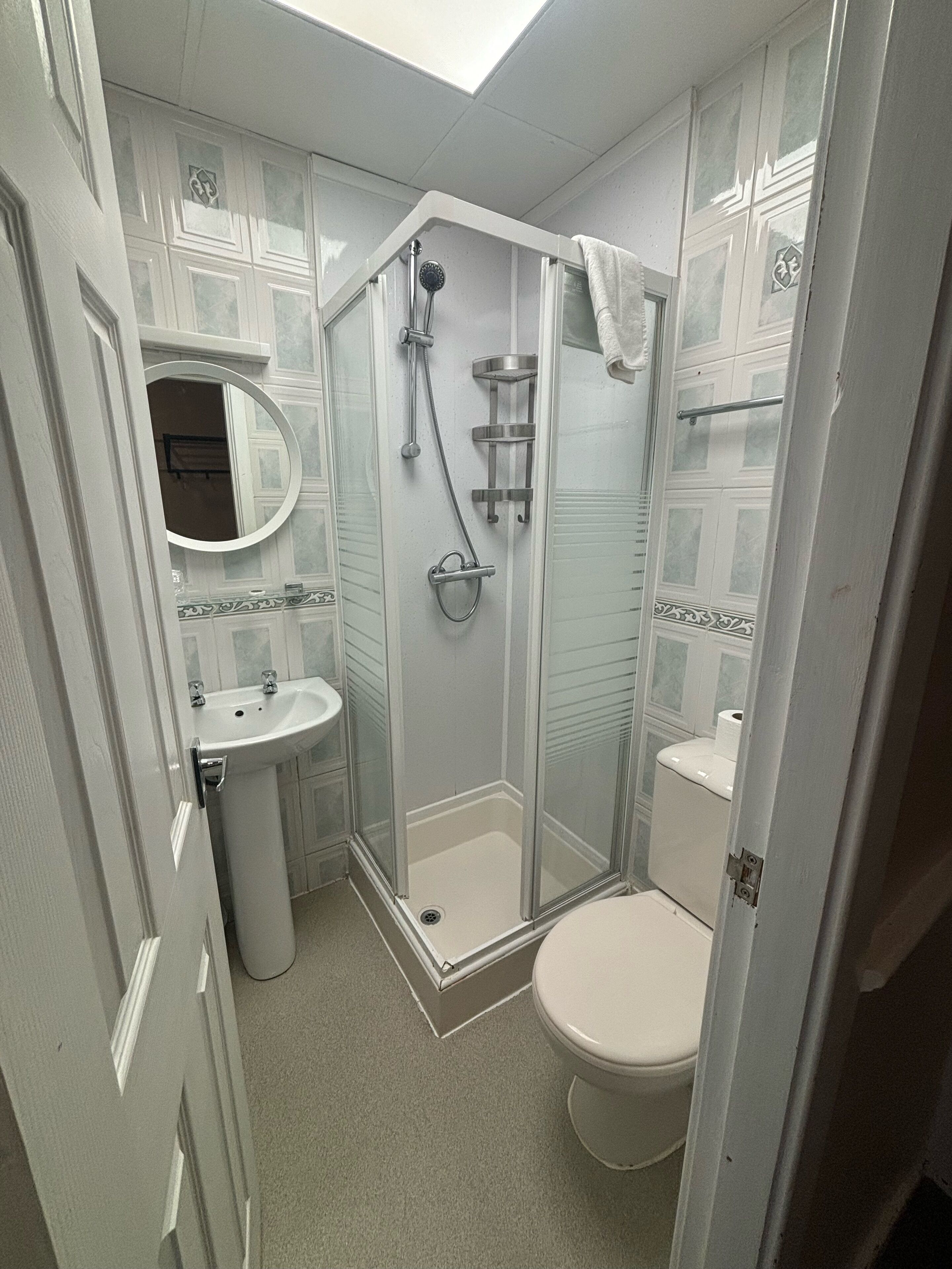 A bathroom with a glass-enclosed shower, a pedestal sink, and a toilet.