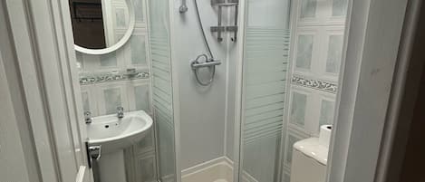 A bathroom with a glass-enclosed shower, a pedestal sink, and a toilet.