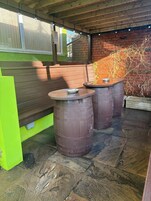 Een terras met houten banken en metalen vaten.