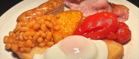 A plate of breakfast food including toast, eggs, beans, bacon, and tomatoes.