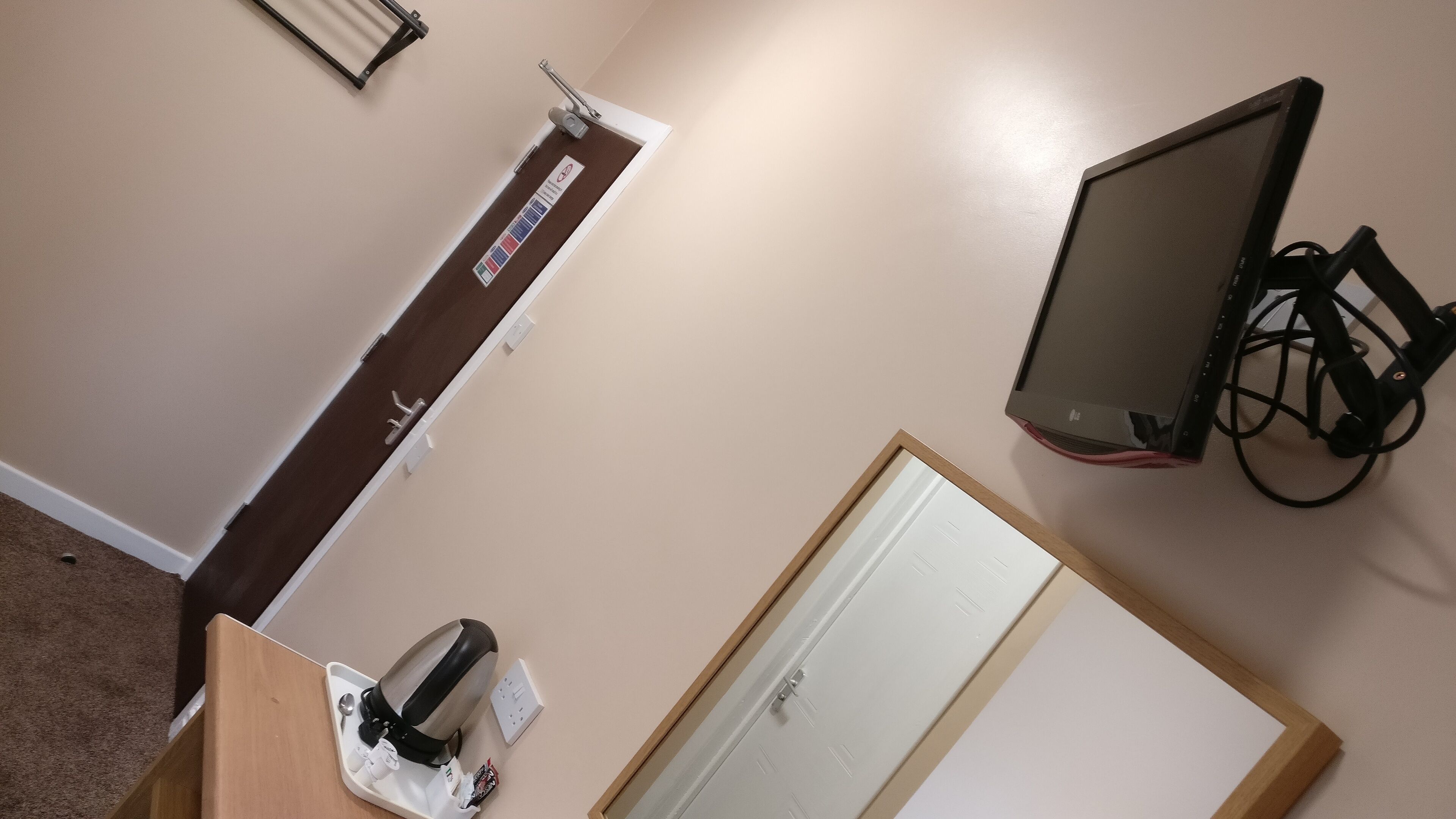 A room with a desk, a chair, a computer monitor, and a door.