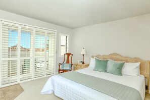 Relax in this serene bedroom with a large bed, nightstand, and comfortable chair.