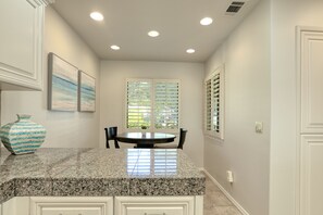 Enjoy meals in this kitchen with a dining table and chairs, a granite countertop, and a decorative vase.