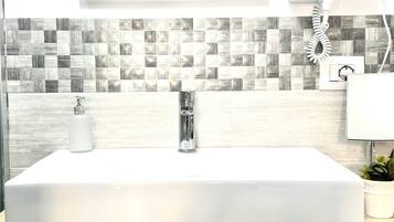 A bathroom with a white sink, a mirror, and a patterned backsplash.